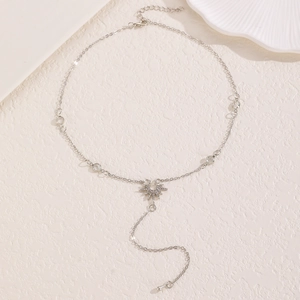 Détail du collier pendentif soleil argenté avec cristaux sur surface texturée beige