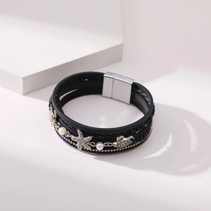 Detail of bohemian layered leather bracelet with silver starfish and sea turtle charms