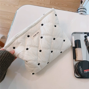Close-up of white quilted cosmetic bag with black polka dots and soft fabric texture