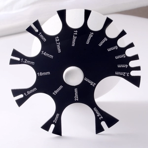 Detail view of black acrylic body jewelry gauge tool with precise white scale markings