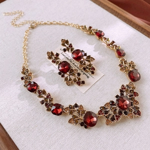 Macro shot of vintage leaf necklace and red gemstone earrings with gold finish