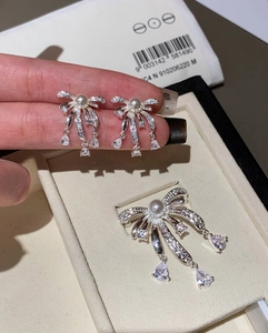 Detailed view of silver bow pearl earrings and brooch set with sparkling tassel drips