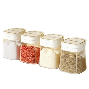 Set of four glass spice jars with gold trim lids, organized for kitchen countertop storage