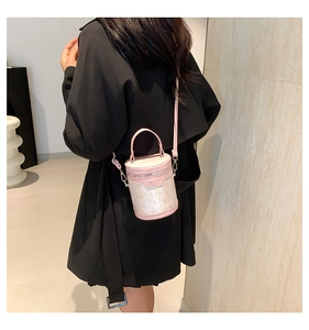 Detail of pink cylindrical bucket bag with marble texture shown on a black coat