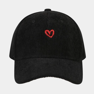 Close-up of red heart embroidery on black corduroy baseball cap texture