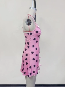 Detailed close-up of pink heart-print camisole dress with lace trim and bow accents