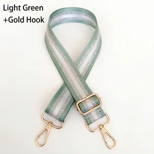 Detail of light green nylon bag strap with silver stripes and gold metal swivel hooks