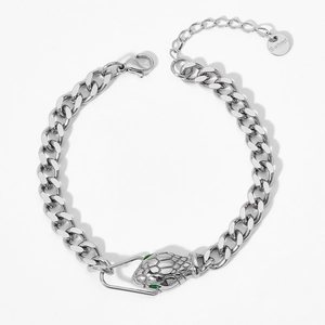 Detailed close-up of silver Cuban link bracelet with green-eyed snake head pendant