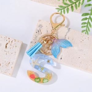 Detail view of ocean-themed resin letter S keychain with blue tassel and mermaid tail