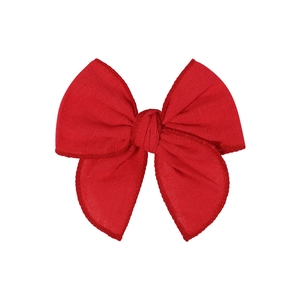 Detail of red fabric bow hair clip with cotton linen texture and stitched edge finish