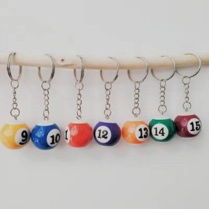 Row of colorful numbered resin billiard ball keychains hanging on a wooden stand