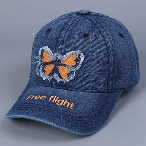 Detail of embroidered orange butterfly and 'Free flight' text on denim baseball cap