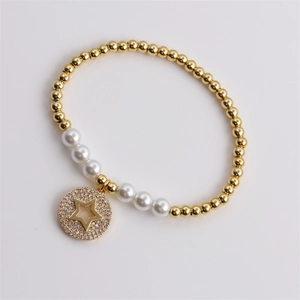 Gold beaded bracelet with pearls and zircon star charm on white background