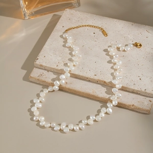 Detailed view of Baroque freshwater pearls with gold extension chain on stone background