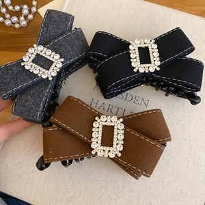 Detailed close-up of wool bow hair claws with rhinestone buckle and fine stitching