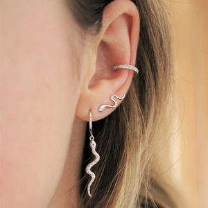 Close-up of silver snake earrings and ear cuff with zircon diamonds on model ear