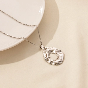 Detailed macro view of a silver irregular hammered hollow circular pendant on a thin metal chain