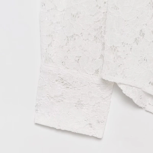 Close-up detail of white lace sleeve cuffs featuring delicate hollow-out floral patterns