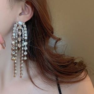 Close-up of sparkling silver tassel drop earrings with crystal heart detail on model