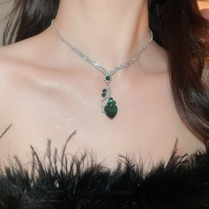 Close-up of heart-shaped green gemstone necklace with pavé diamonds on a model
