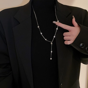 Detail of silver Y-shaped long necklace with sparkling rhinestones on black sweater