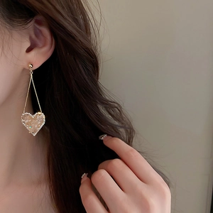 Side view of elegant gold long drop heart earrings with light brown stone inlay