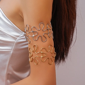 Detailed view of gold and silver hollow floral metal arm cuffs worn on the upper arm