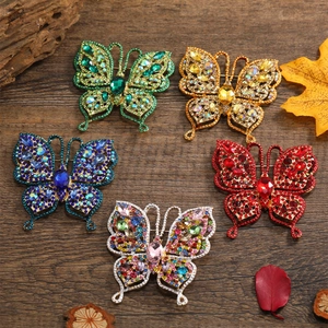 Cinq broches papillon vintage serties de strass sur un bureau en bois rustique