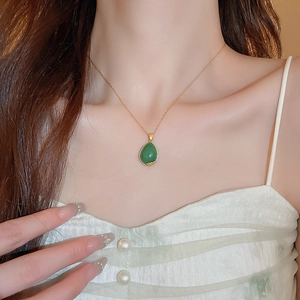 Detail shot of a teardrop green gemstone pendant on an elegant gold plated chain