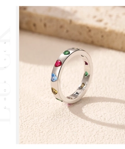Macro shot of silver ring with colorful heart-shaped stones on beige stone background