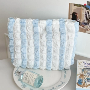Detail showing blue and white striped bubble puff texture of this spacious makeup bag