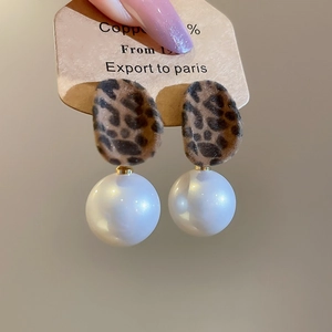 Detailed view of leopard print plush earrings with a large round pearl pendant