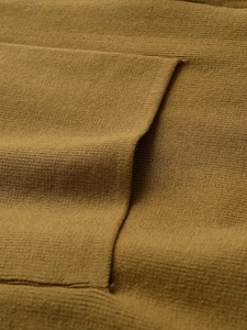 Dettaglio ravvicinato del tessuto a maglia fine giallo senape con cuciture precise