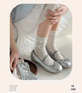 Detail of knit crew socks with delicate white bows in cream, grey, and pink tones