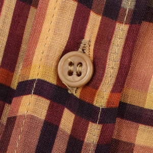Gros plan sur la texture du tissu en lin à carreaux et le détail du bouton