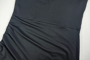 Detailed macro view of side ruching and pleated texture on black slim fit dress