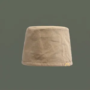 Detailed close-up of khaki cotton bucket hat featuring a small metal tag and twill texture