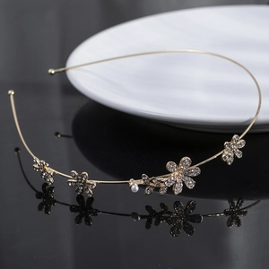 Elegant gold metal headband with rhinestone flowers and pearl on dark mirror surface
