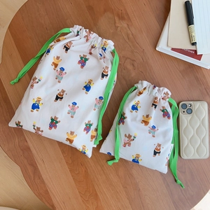 Set of two cotton drawstring bags with bear print patterns on a natural wood table