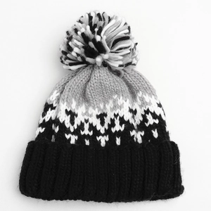 Detail of the knit winter hat featuring a multi-color pompom and geometric diamond pattern