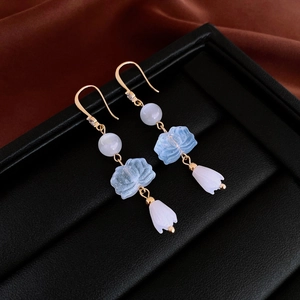 Detail of gold-plated lotus flower earrings with blue petals and zircon accents