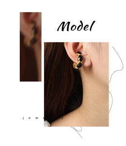 Detail of vintage gold-plated hoop earrings with black enamel inlay on female model