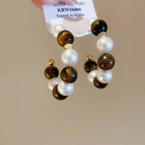 Détail de boucles d'oreilles en C avec perles d'oeil de tigre et perles sur étiquette Argent 925