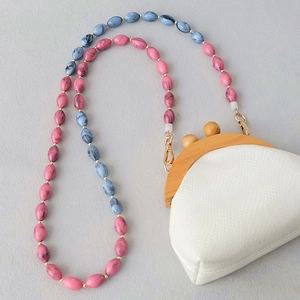 Détail de la bandoulière à billes marbrées rose et bleu avec fermoir en bois