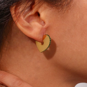 Detail of gold geometric earrings with micro-p镶嵌ed green crystals on a model's ear