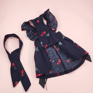 Flat lay detail of pet navy cherry print dress and matching bandana on pink background