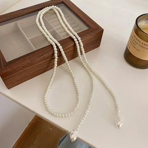 Long collier de perles élégant avec pendentif baroque sur un écrin à bijoux en bois sombre