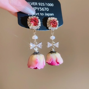 Detail of zircon butterfly earring with pink rose bud pendant and silver needle