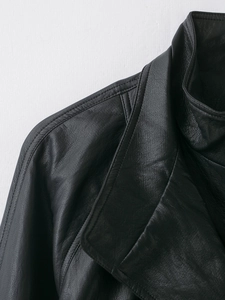 Detailed close-up of the lapel and shoulder stitching on a black faux leather jacket