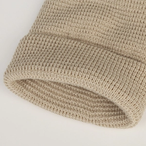 Vista macro dettagliata della trama a maglia beige di un berretto invernale con risvolto